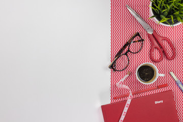 Fashion designer workplace. Modern white office desk table with a notebook diary, pen, eyeglasses and cup of coffee. Top view with copy space, flat lay.