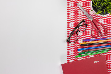 Fashion designer workplace. Modern white office desk table with a notebook diary, eyeglasses and colorful pens. Top view with copy space, flat lay.