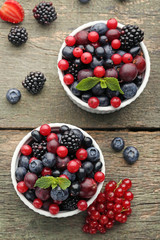 Ripe and sweet berries in bowls on wooden table