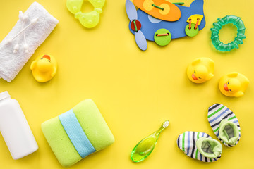 Baby care with bath set, ducklings and towel on yellow backgroun