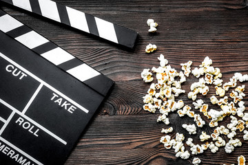 Watching the film. Movie clapperboard and popcorn on wooden tabl