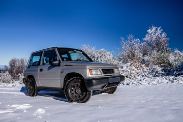 Fototapeta na wymiar An offroad car on the snow in the mountains