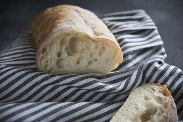 ciabatta cut on a textile napkin on a dark background 