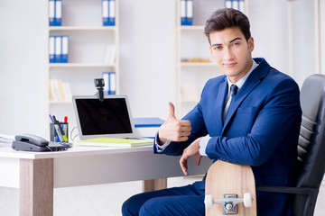 Young businessman with skate in office in sports concept