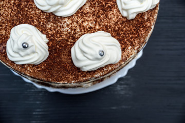 sour cream cake with cream on a dark wooden background