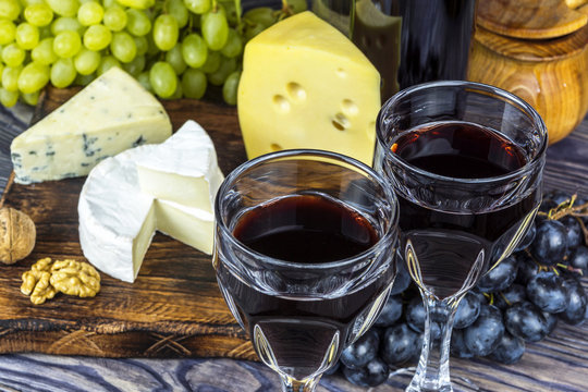 Two glasses of red wine with fruits, cheeses, honey and walnuts