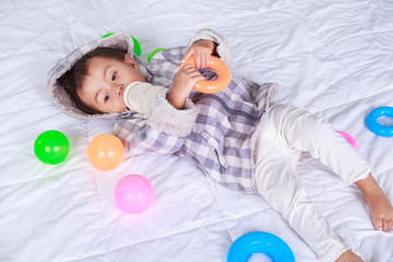 baby drinking milk with bottle on bed