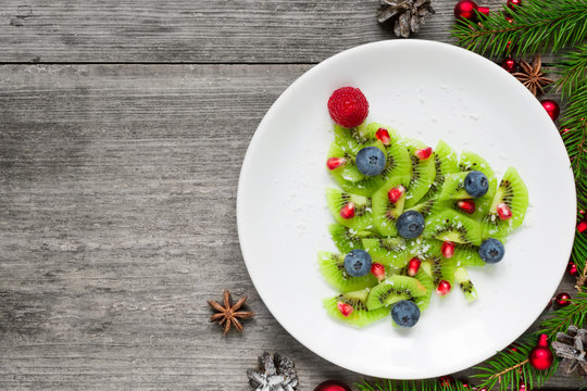 kiwi christmas tree with berries, pomegranate seeds and coconut looks like snow. funny food idea for kids