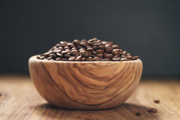 Fototapeta na wymiar roasted coffee beans in wood bowl on table with dark background