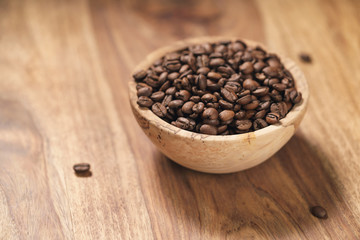 roasted coffee beans in wood bowl on table with dark background