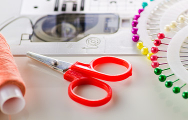 Scissors, needles, thread, a sewing machine closeup