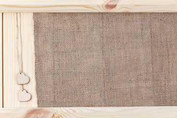 Two heart on a wooden background covered with burlap, a card for Valentine's Day.