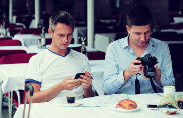  men sitting with coffee and looking photos at the table