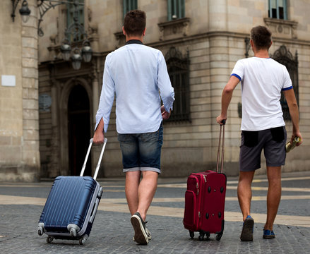 Rear view of two guys with luggage
