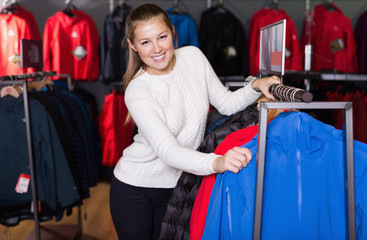 Young positive woman choosing sport clothes