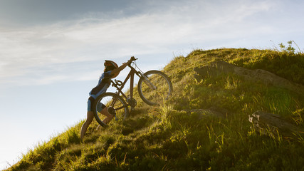 Obraz premium Biker pushes bicycle up in the mountains