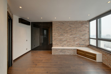 A part of the room with a red brick, glass black doors and a white wall
