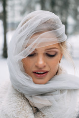 Obraz premium Beautiful woman portrait on the snowy pine forest in grey veil on the face