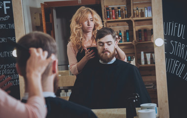 Master cuts hair and beard of men, hairdresser makes hairstyle for a young man. Hipsters
