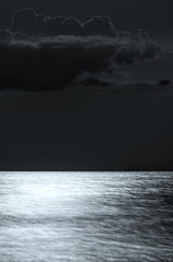 clouds over the sea at night. moonlight on the waves, horizon. Long exposure. black and white photo