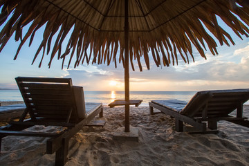 Sun loungers with umbrella on the beach, sunrise