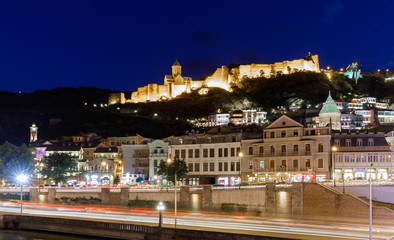 Amazing night view of Olt town with Narikala ancient fortress and the embankment with blurred lights of traffic , St Nicholas Church in night Illumination, Tbilisi, Georgia