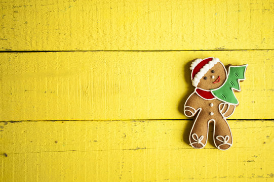 gingerbread man with fir-tree  decorated glaze flat lay on yellow boards.