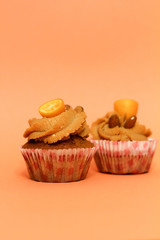 Cream caramel cupcake on orange background decorated by almonds