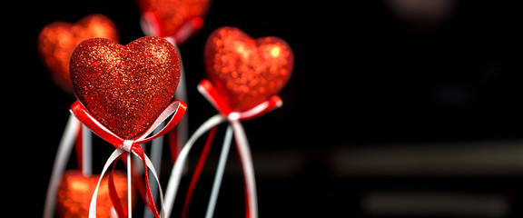 Valentines day. Red hearts on black blurred background close-up with copy space for congratulation, border design panoramic banner 