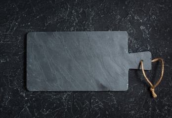 Black old-fashioned stone and slate cutting board on black background