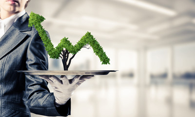 Hand of waitress presenting growing graph on tray.