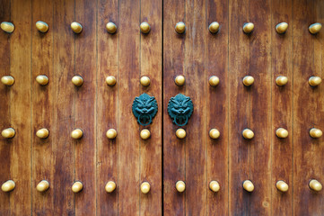 Chinese traditional doorknob and wooden doors. Old handle of metal on a wooden old door. Door knocker in the shape of a lion