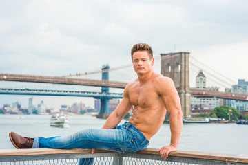 Man’s Beauty in New York. Shirtless, half naked, waring jeans, Strong, sexy guy casually sitting...