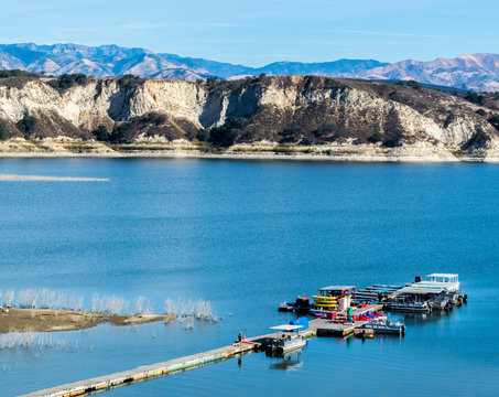 long wooden pier with boats at California's Lake Cachuma with San Rafael Mountains in the distance