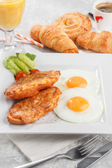 Bread fried in cheese served with fried eggs, lettuce and tomato. Breakfast conception with fresh orange juice, coffee and baked goods