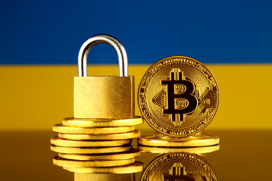 Physical version of Bitcoin, golden padlock and Ukraine Flag. Prohibition of cryptocurrencies, regulations, restrictions or security, protection, privacy.