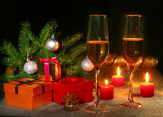 Christmas composition with Glass of sparkling champagne wine or cognac, christmas candles, colorful balls, gift box and tree on a sparkling background. New Year decoration.