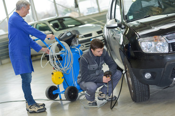 student and senior mechanic checking tyre pressure at automotive shcool © auremar