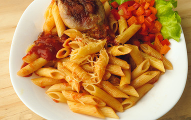 Italian pasta with vegetables and arugula close-up