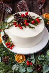 Homemade white cream naked cake decorated with white cream, cones and red berries.