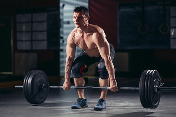 Closeup portrait of a muscular man workout with barbell at gym. cross fit and fitness