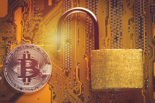 Bitcoin cryptocurrency with opened padlock on computer motherboard. Crypto currency - electronic virtual money for web banking and international network payment. Close up image with focus on bitcoin.