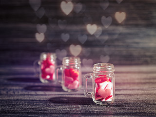 Small hearts of cloth are in three glassware. Fantasy background to Valentine's Day or other love event