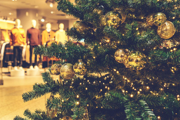 Fototapeta premium christmas tree in a mall with shopping clothes in the background