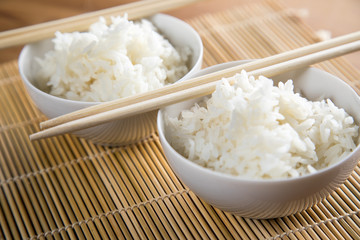 Zwei Schalen Basmati Reis mit Stäbchen auf Matte