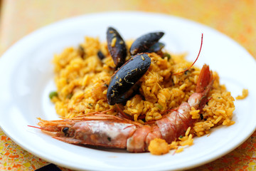 delicious rice dish with mussels and royal prawns on white plate