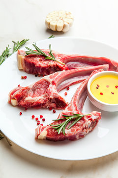 Raw lamb ribs with ingredients for cooking on white marble table