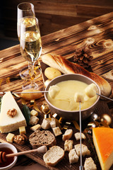 Gourmet Swiss fondue dinner on a winter evening with assorted cheeses on a board alongside a heated...