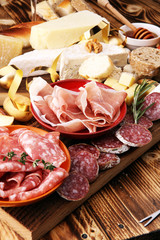 assorted cheese,meats and bread on wooden background