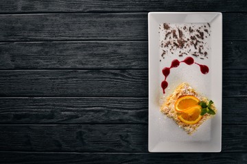Layered cake with orange flavor. On a wooden background. Free space for your text. Top view.